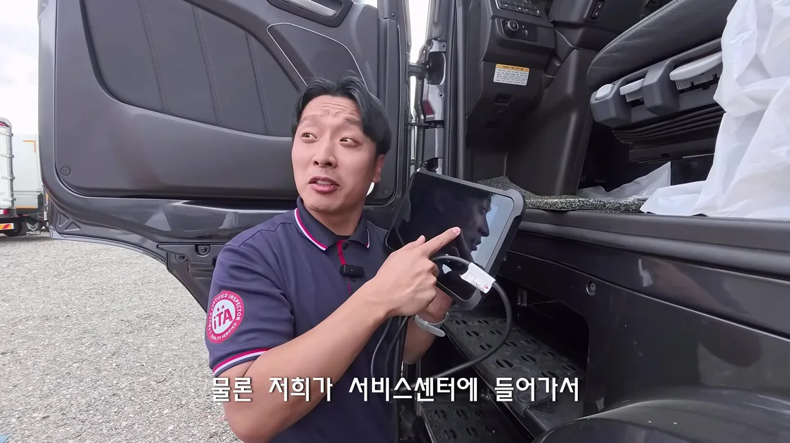 운전석 문을 연 엑시언트 옆에서 케이블이 연결된 진단기 태블릿을 들고 화면을 가리키는 이동선 수석실장