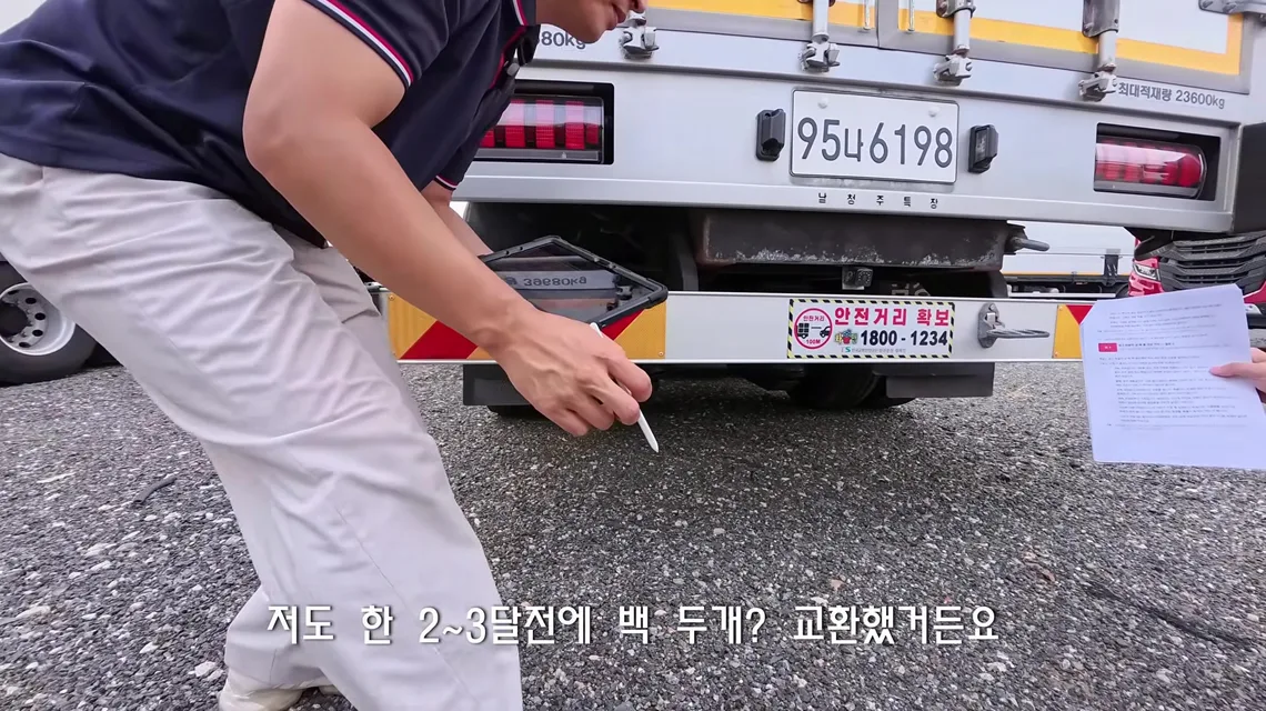 윙바디 화물차 후면 번호판 아래로 몸을 숙여 펜으로 하부를 가리키는 이동선 수석실장